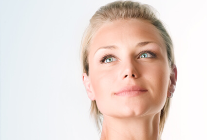 Picture of a woman with blonde hair, facing the camera, and happy with her perfect face lift procedure she had at Top Plastic Surgeons in beautiful San Jose, Costa Rica.  The woman is looking slightly upwards to show her satisfaction with her face lift.